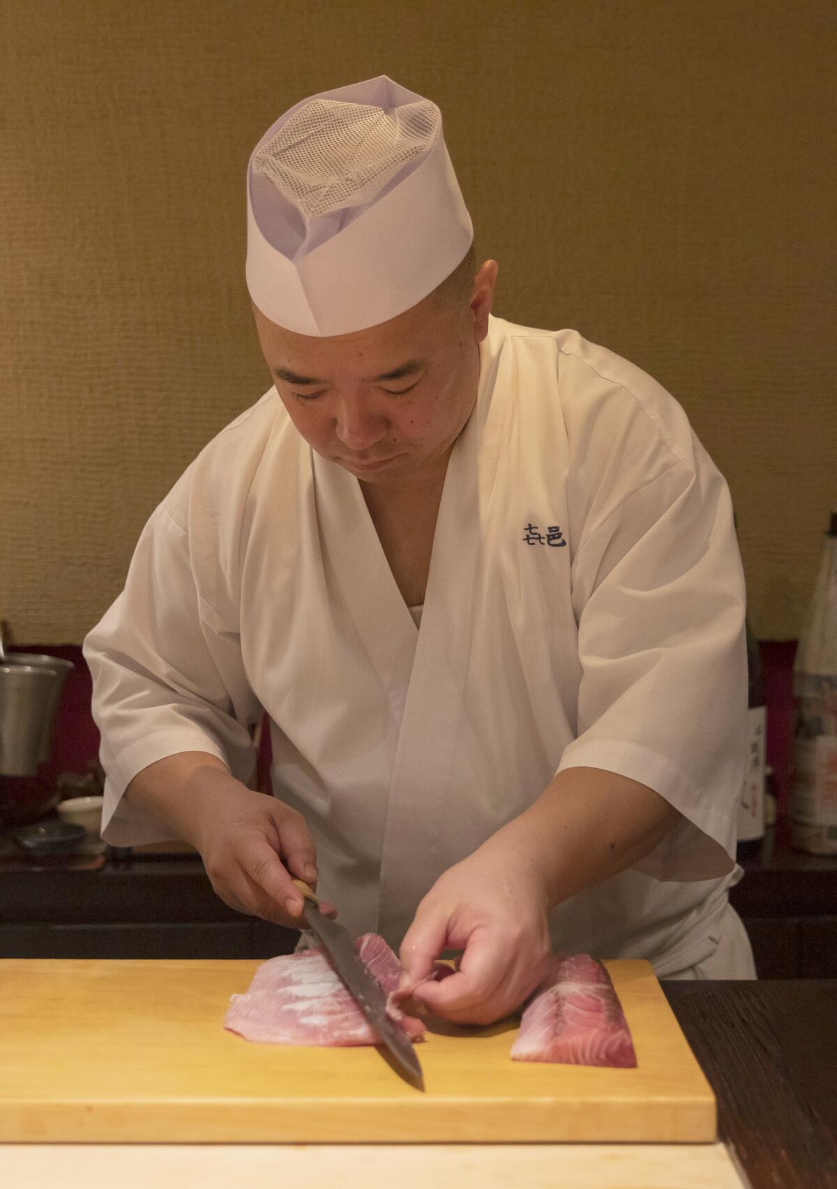 Koji Kimura trims a piece of fish before service.