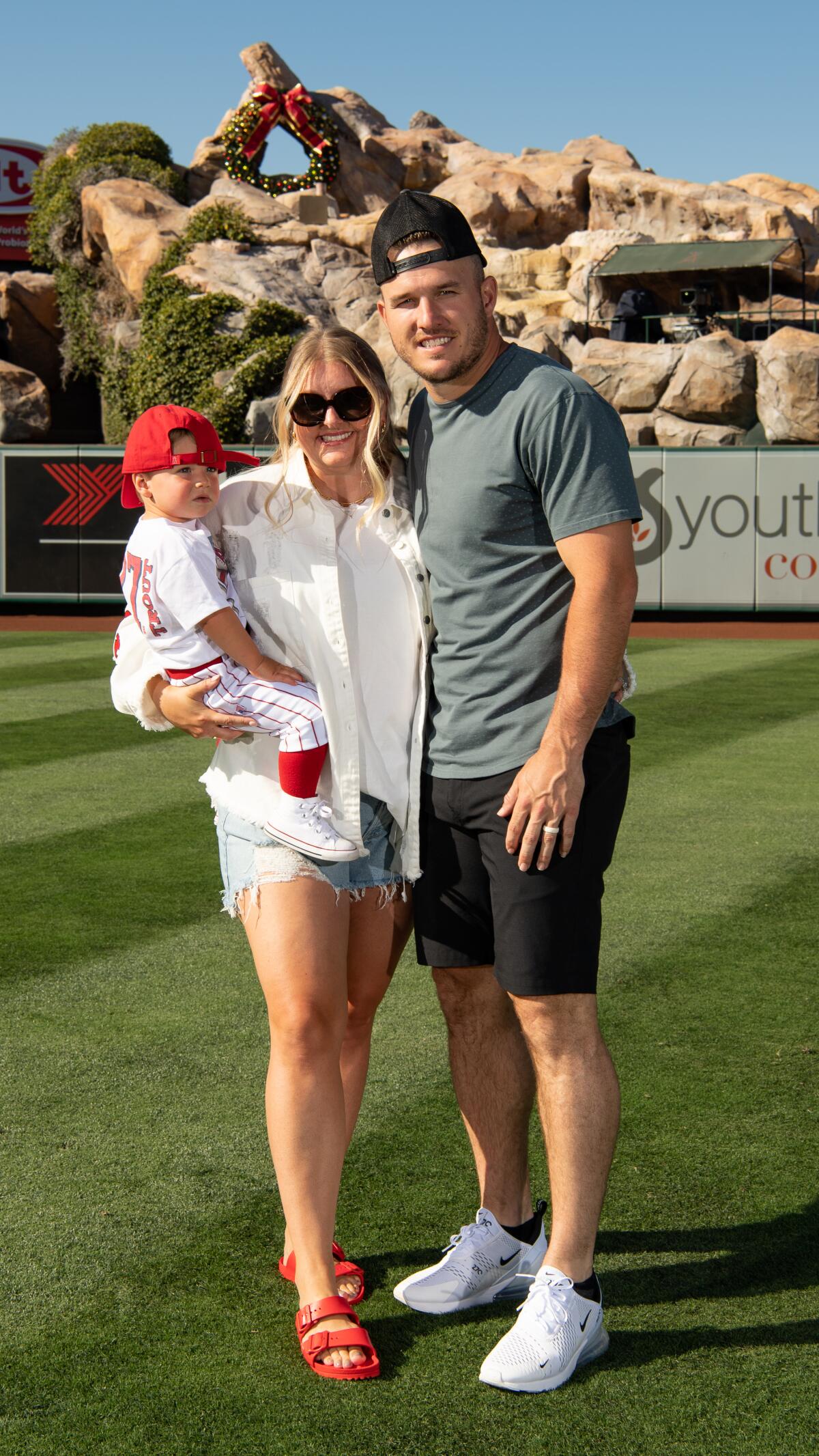 Mike Trout, from right, stands in the outfield with his wife Jessica Cox and child Beckham Aaron Trout