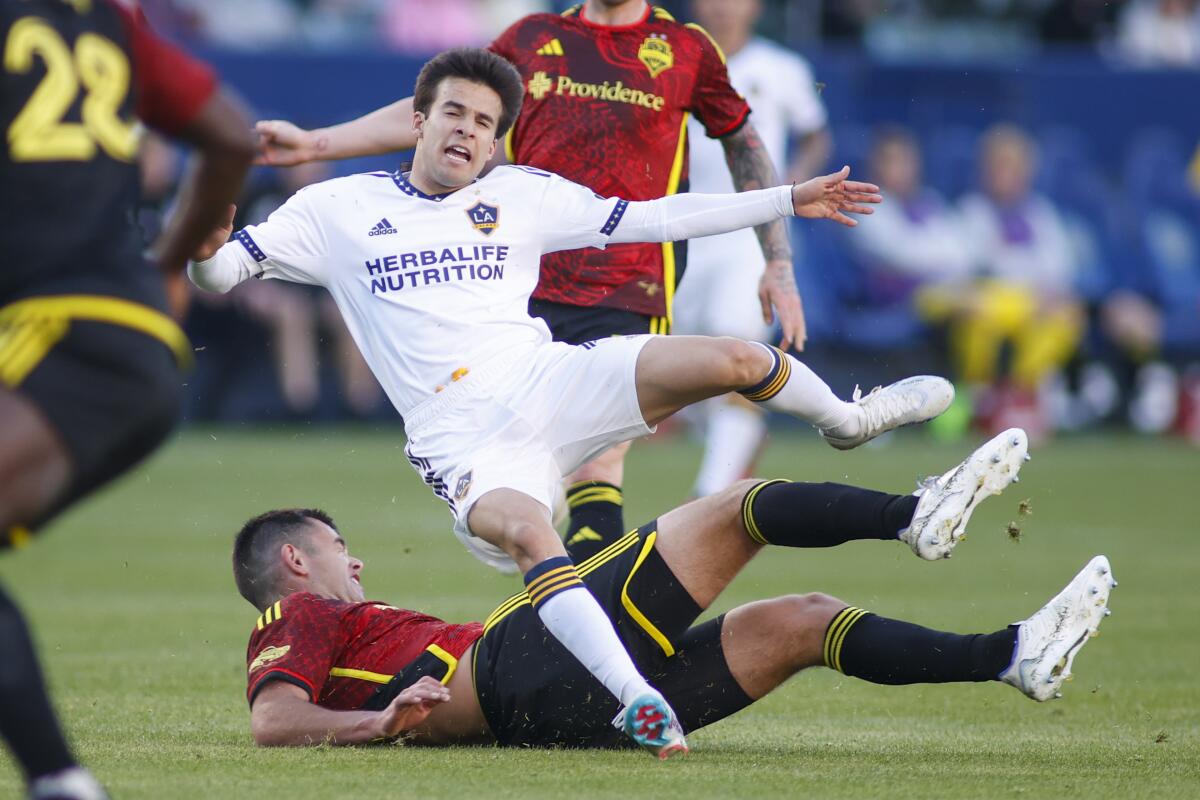 Galaxy midfielder Riqui Puig leaps over Seattle Sounders midfielder Obed Vargas during a match on April 1.