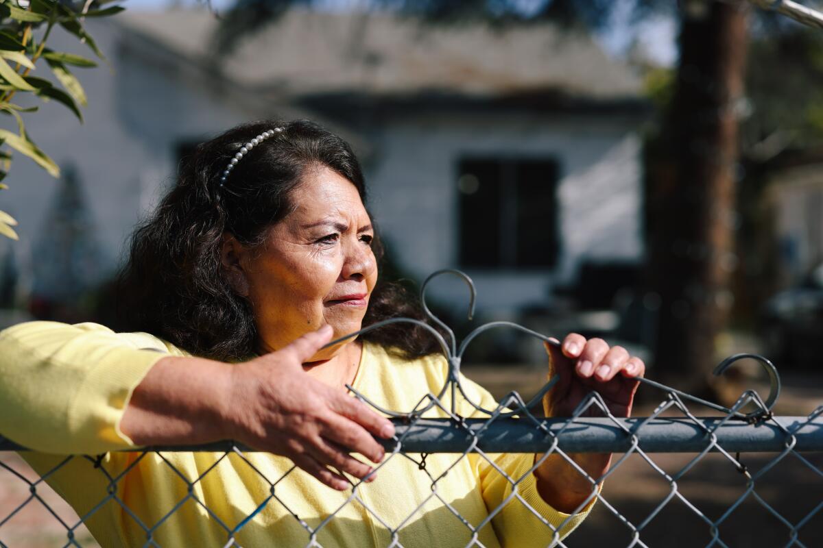 A woman stands behind a chain link fence.