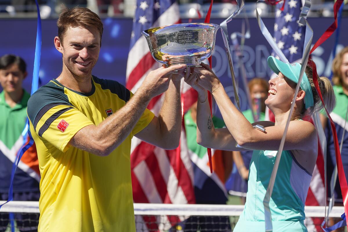 John Peers, left, and Storm Sanders, of Australia, hold up the championship trophy after winning the mixed doubles final against Kirsten Flipkens, of Belgium, and Edouard Roger-Vasselin, of France, at the U.S. Open tennis championships, Saturday, Sept. 10, 2022, in New York. (AP Photo/Matt Rourke)