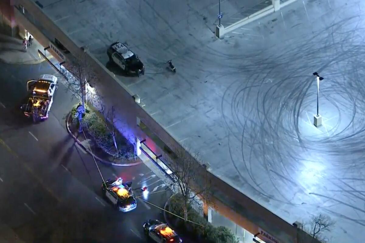 Aerial view of police cars at a parking structure, with tire marks covering the top level