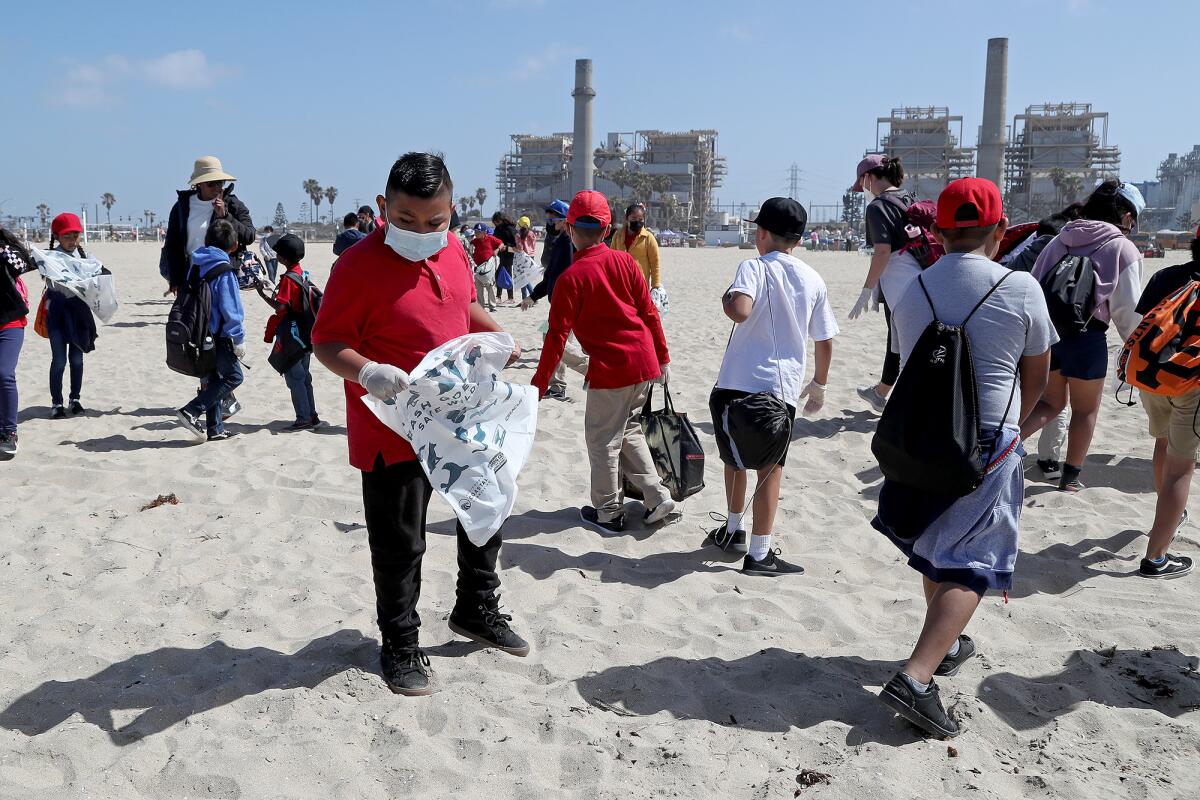 Children pick up trash on a beach and put it into bags