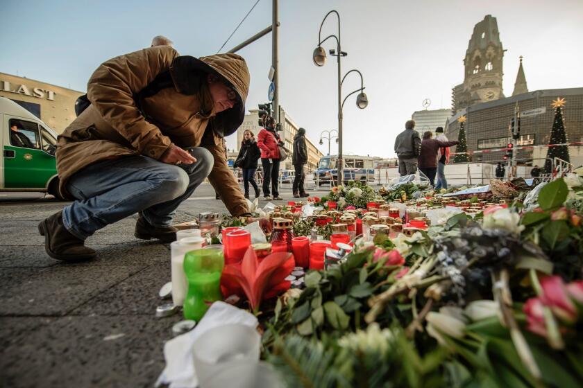 A mourner places a candle at a makeshift memorial near the Kaiser Wilhelm Memorial Church in Berlinon Dec. 21, 2016, close to the site where a truck crashed into a Christmas market two days before.