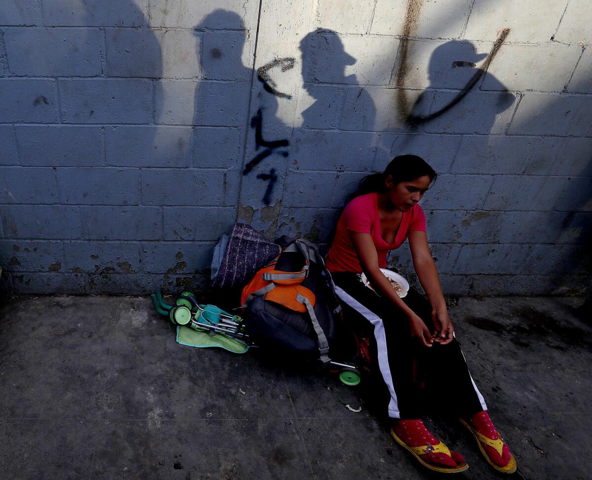 A Honduran woman eats a hot meal outside the Benito Juarez Sports Center in Tijuana.