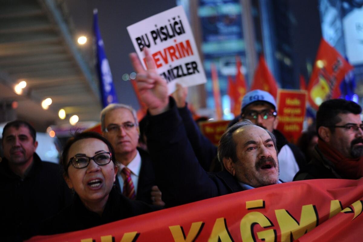 A Turkish protester holds up a placard reading "Only revolution can clear this corruption" as others chant slogans during a demonstration in Istanbul on Dec. 30 against the government of Prime Minister Recep Tayyip Erdogan.