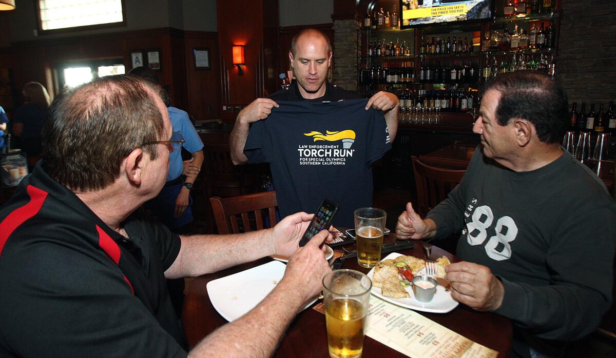 John Bordeaux and Ron Calbrisi of Toluca Lake listen to Burbank Sgt. Jeff Lamoureaux describe what a donation to the Special Olympics could get them at Claim Jumper in Burbank, where the officers from the Burbank Police Department helped with tables as a fundraiser for the Special Olympics on Thursday, April 17, 2014.