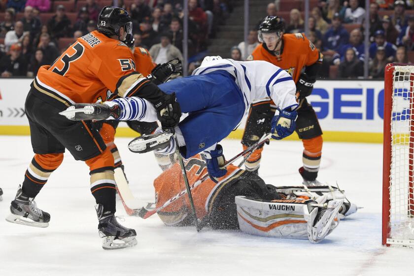 Maple Leafs center Nazem Kadri, top center, goes airborne as he tries to score on Ducks goalie John Gibson, below, while under pressure from defensemen Shea Theodore, left, and Josh Manson during the first period.