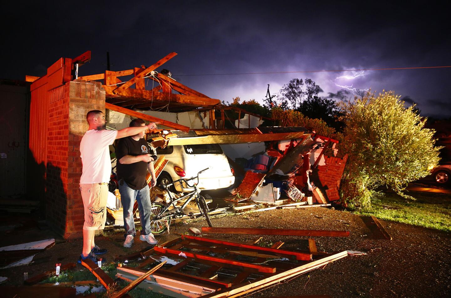 Derrek Grisham, left, points out neighborhood damage to storm chaser Travis Schafer after a tornado damaged his mother's house in Cleburne, Texas.
