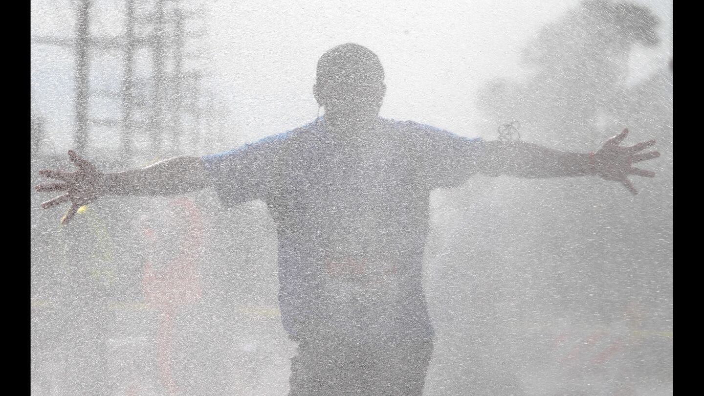 A race participant runs through water sprayed by firefighters at the 19th mile during 30th Los Angeles Marathon.