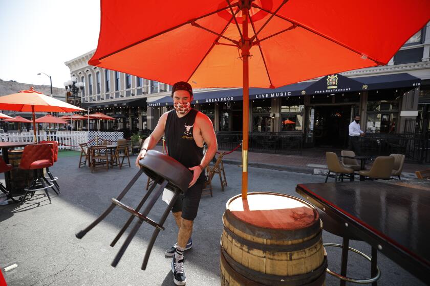 Bob McCarthy sets out seating for Henry's Pub & Restaurant on 5th Ave. in the Gaslamp Quarters. 5th Ave. is closed down several days a week to allow restaurants to put seating in the street. (K.C. Alfred / The San Diego Union-Tribune)