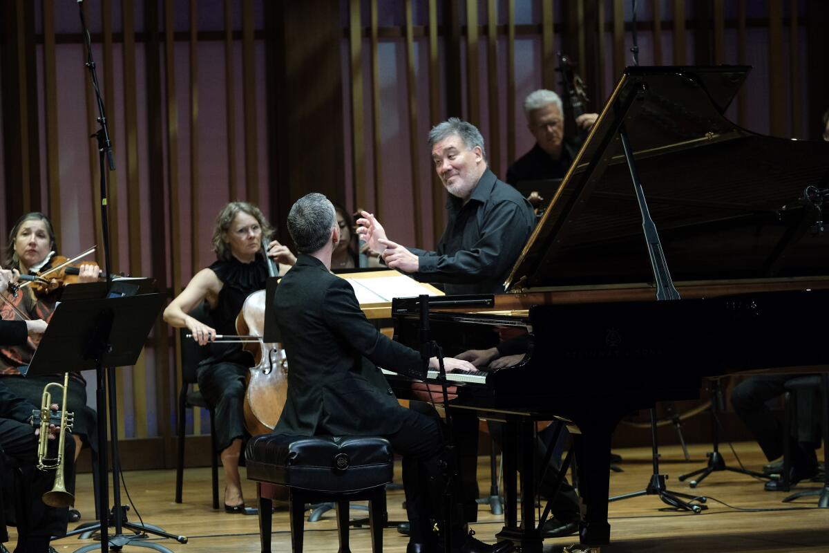 Conductor Alan Gilbert, right, and pianist Inon Barnatan look at each other during a concert. 