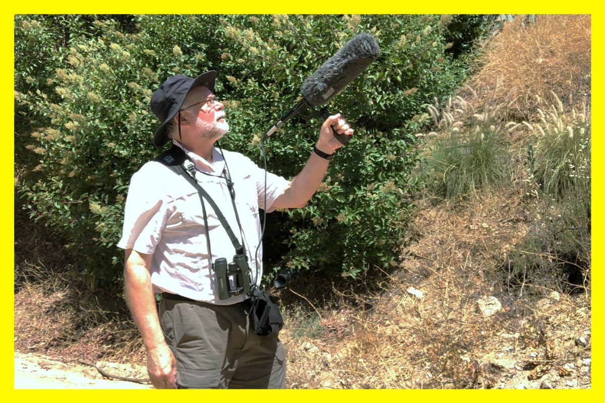 A man holds a microphone while recording birdsong.