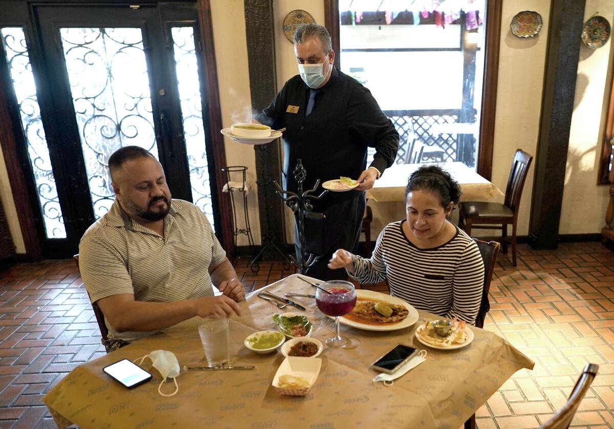 FILE - In this Wednesday, March 10, 2021 file photo, waiter Jose Bravo, center, delivers food for Alberto Castaneda, left, and his wife, Esther, at Picos restaurant in Houston. The Institute for Supply Management, an association of purchasing managers, reported Monday, April 5 that the U.S. services sector, which employs most Americans, recorded record growth in March as orders, hiring and prices all surged. (AP Photo/David J. Phillip, File)