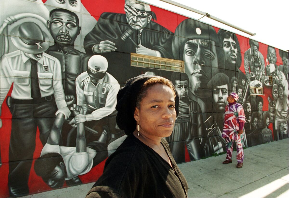 Artist Noni Olabisi, in front of her mural "To Protect and to Serve."