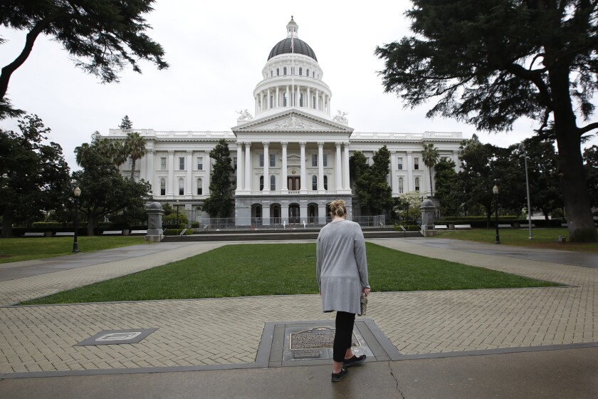A woman looks at a historical marker in front of the state Capitol in Sacramento.