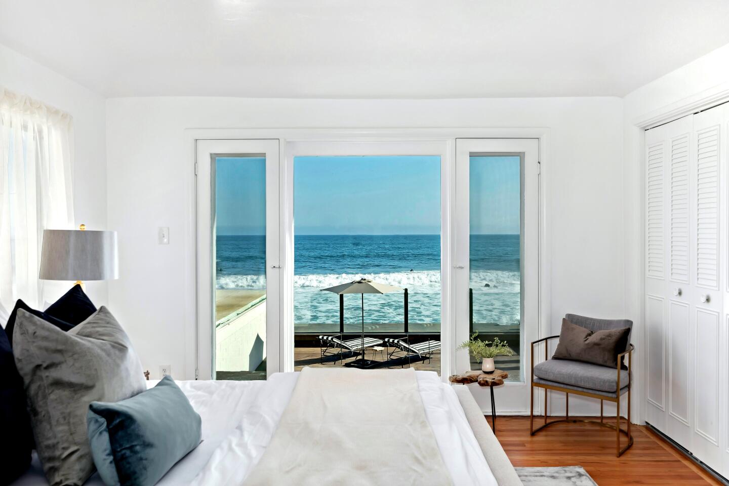 Large windows in a bedroom look onto the ocean.
