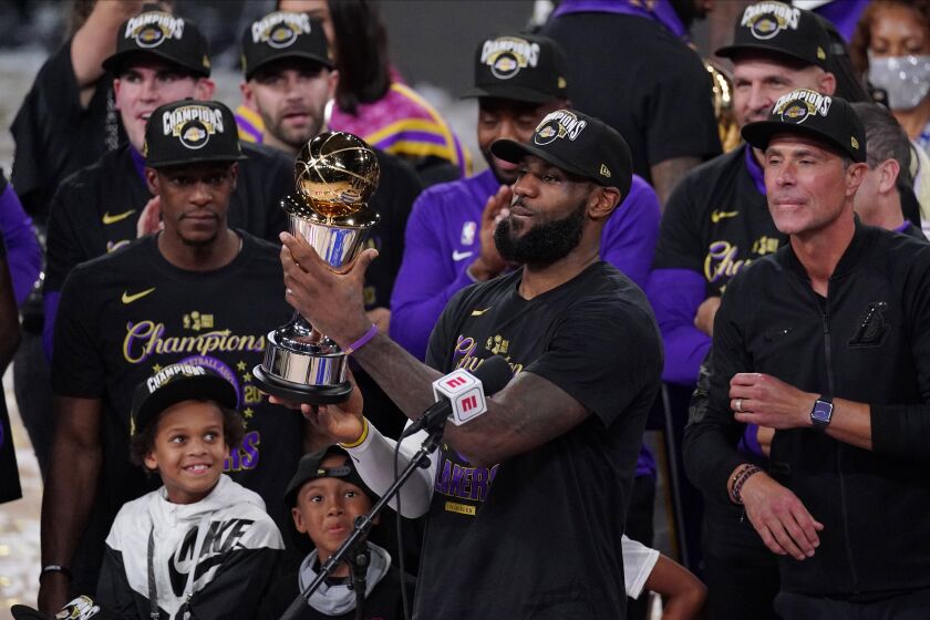 Los Angeles Lakers' LeBron James (23) holds the MVP trophy as he celebrates with his teammates after the Lakers defeated the Miami Heat 106-93 in Game 6 of basketball's NBA Finals Sunday, Oct. 11, 2020, in Lake Buena Vista, Fla. (AP Photo/Mark J. Terrill)