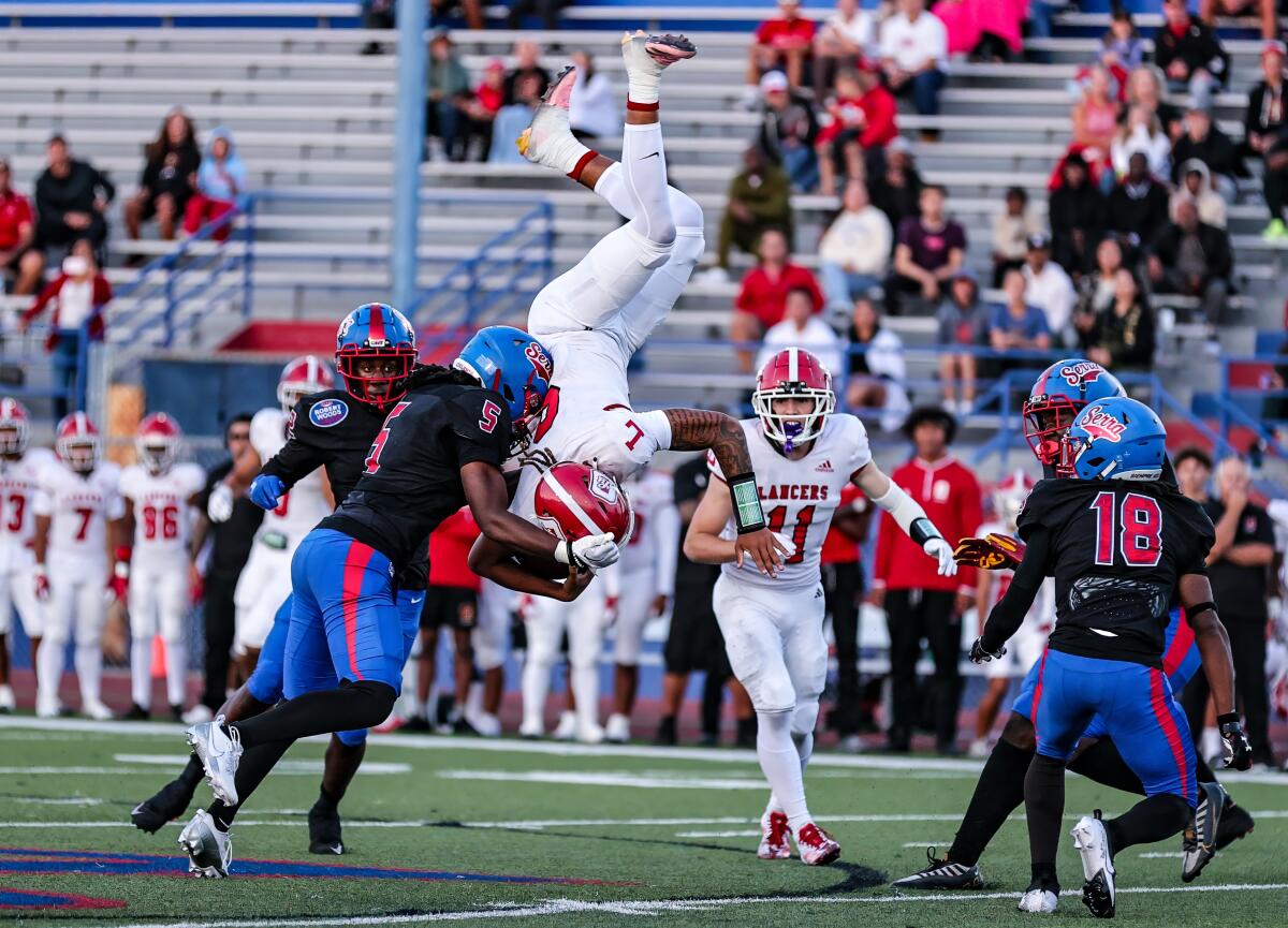 Orange Lutheran quarterback TJ Lateef goes airborne hurdling over Wesley Ace (18) of Gardena Serra.