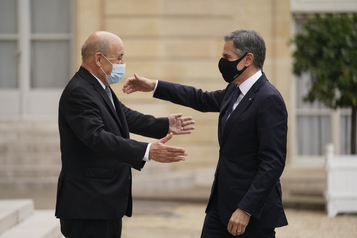 The top U.S. and French diplomats, both wearing masks, embrace