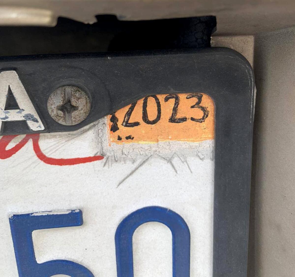 Closeup of a license plate with an orange rectangle and 2023 painted on the corner.