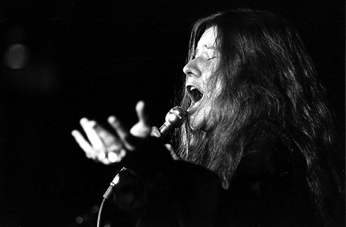 A female rock singer holds a microphone to her mouth.