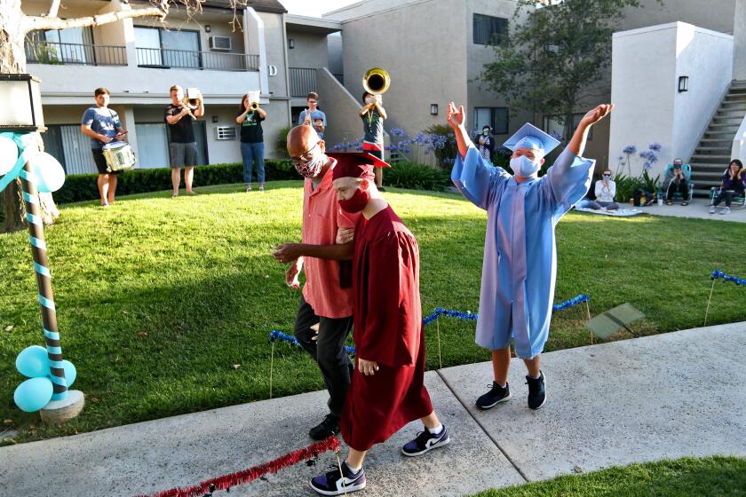 Estancia High School senior Marcus Winters walks with his father Jack Winters as friend aNd his friend Zeke Eampietro, from Corona del Mar HS, follows during small ceremony at Winters' home in Costa Mesa on Saturday, June 13, 2020. Neighbors sat outside and cheered on the special education graduates.