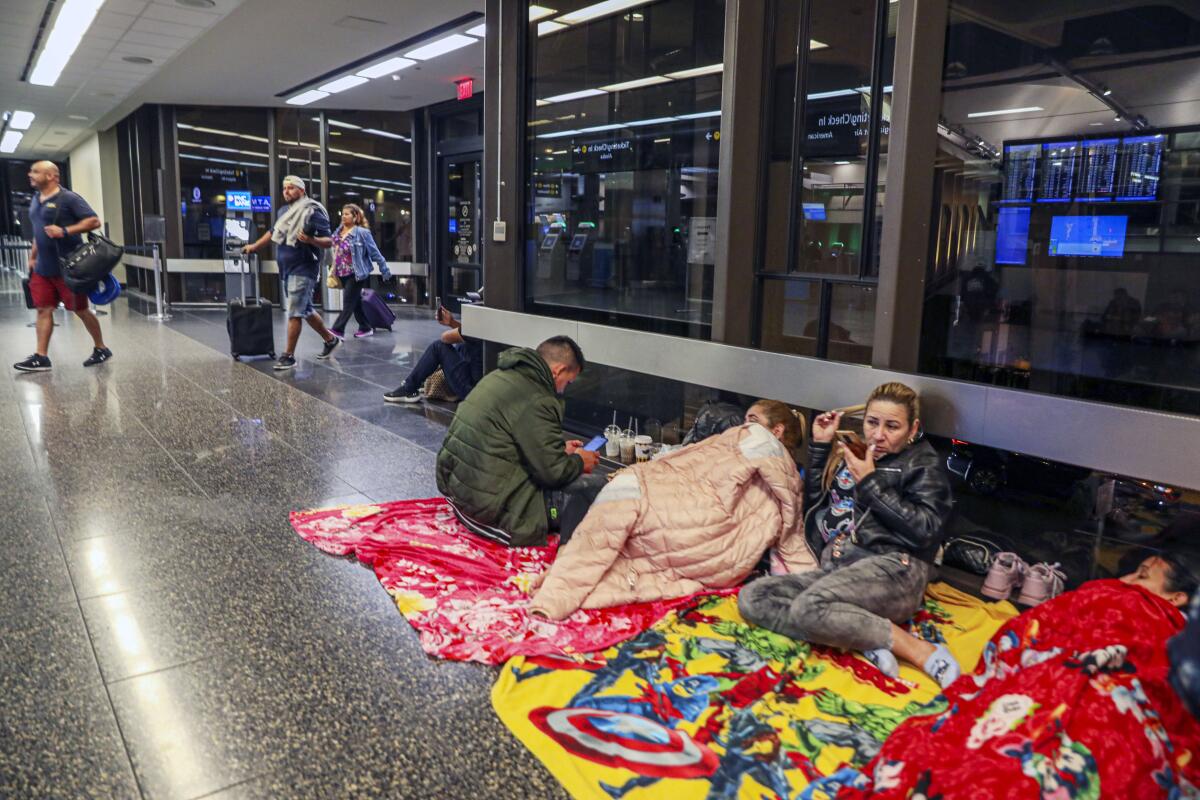 Migrants from Venezuela sit at the San Diego International Airport