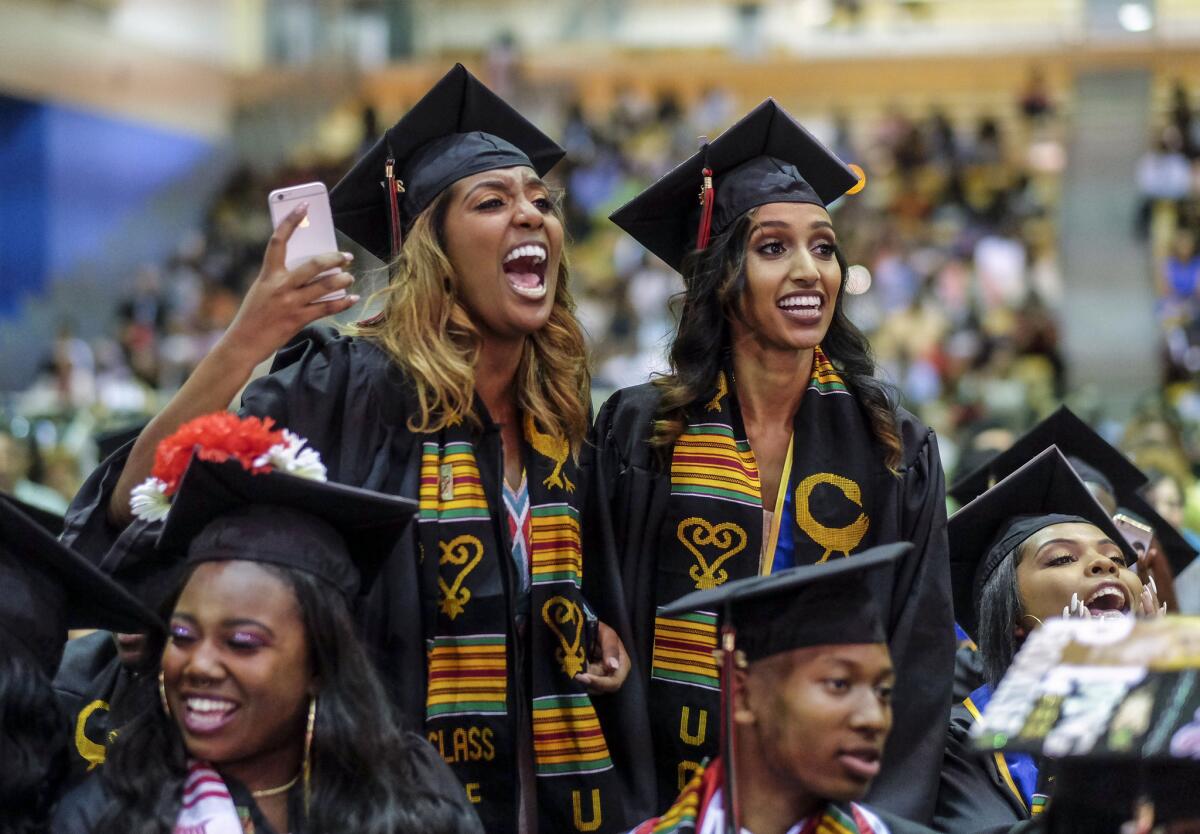 Graduates Namuna Tefera, left, and Bilen Teclemariam react to a speaker during the Black Graduation ceremony at UC Riverside.