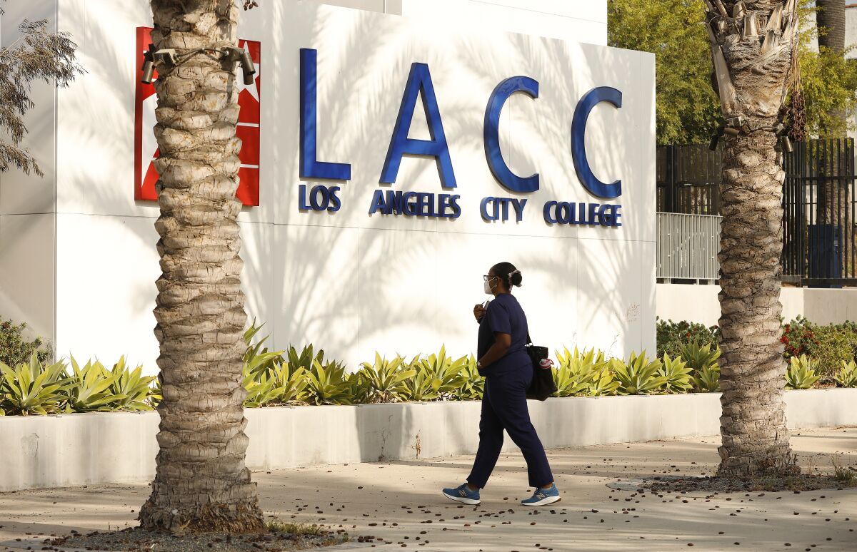 A person walks between palm trees on the campus of Los Angeles City College