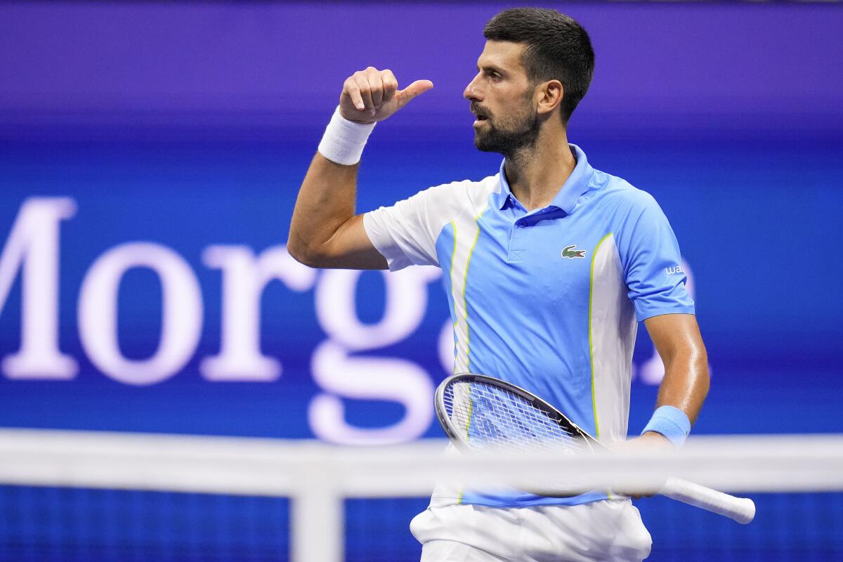 Novak Djokovic holds up his hand to mimic a telephone.