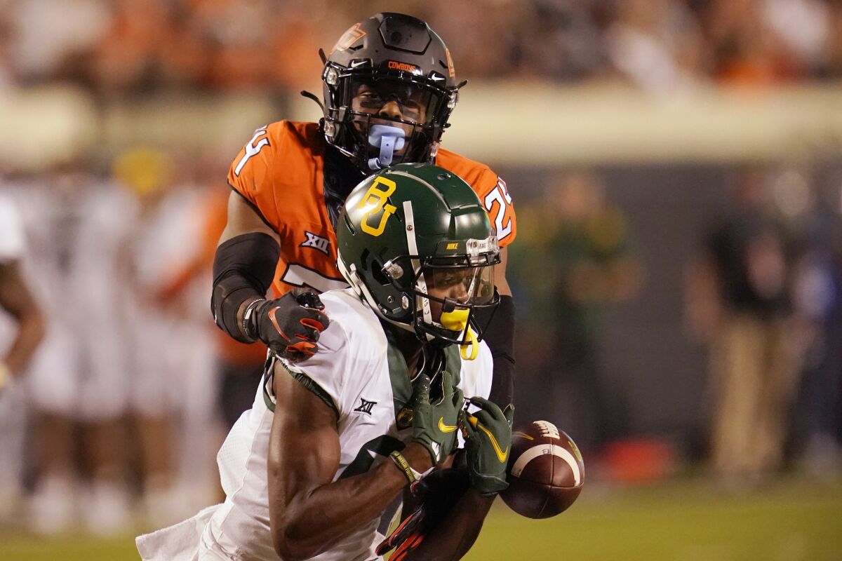 Oklahoma State cornerback Jarrick Bernard-Converse, rear, reaches in to break up a pass intended for Baylor wide receiver Tyquan Thornton in the second half of an NCAA college football game, Saturday, Oct. 2, 2021, in Stillwater, Okla. (AP Photo/Sue Ogrocki)