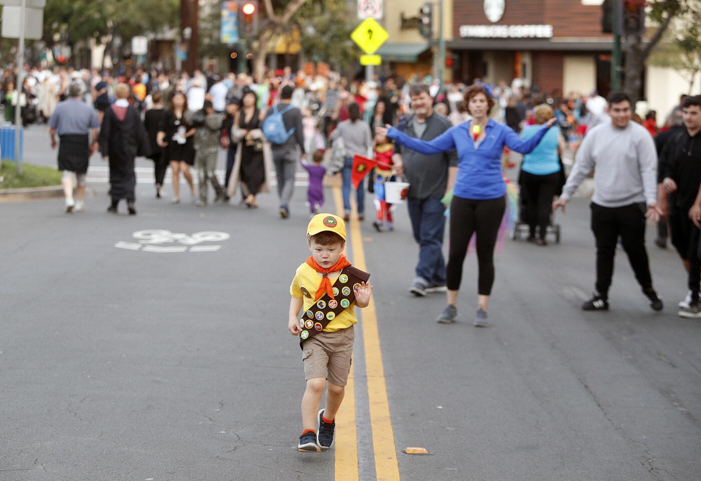 Heather Jones, as her son Max, 3, runs along the yellow stripes on Honolulu Boulevard, calls again and again for him to return at the annual Montrose Halloween Spooktacular on Honolulu Boulevard on Wednesday, October 31, 2018. Honolulu was closed for three blocks where most businesses had their front doors open as a platform for giving hundreds of small and large children candy and Halloween tokens.