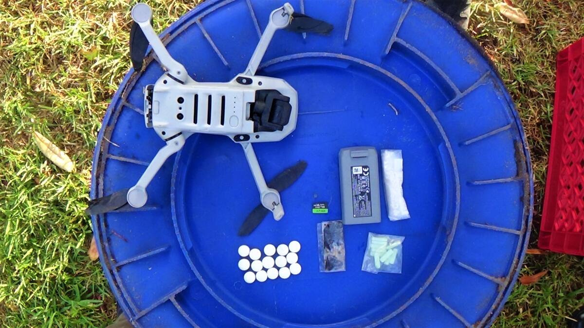 A drone sits beside clusters of drugs.
