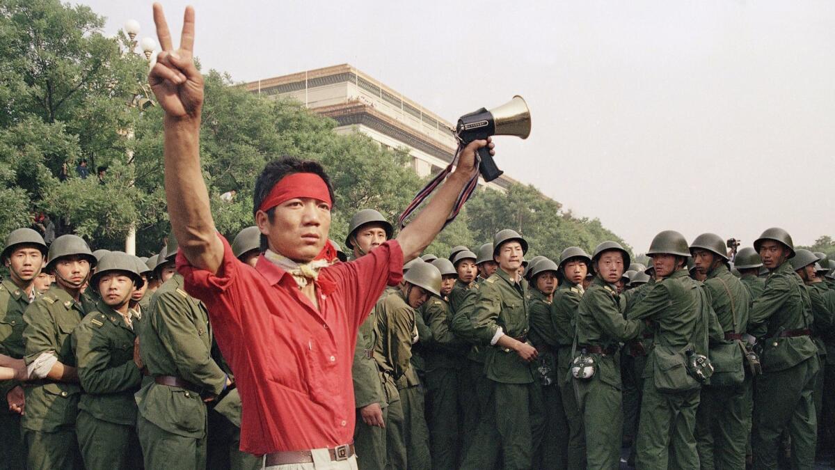 Early June 4, 1989, civilians stand on an army vehicle near Tiananmen Square in Beijing.