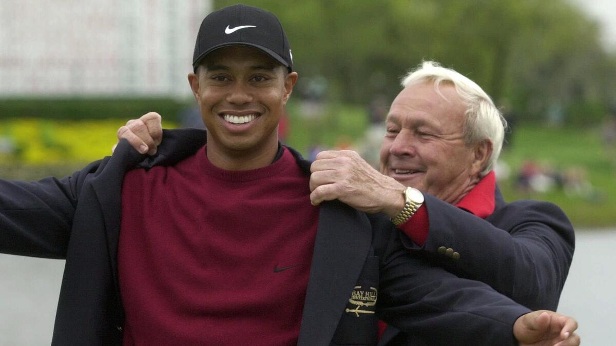 Tiger Woods is helped into his winner's jacket by golfing great Arnold Palmer after taking a victory at the 2001 Bay Hill Invitational in Orlando, Fla.