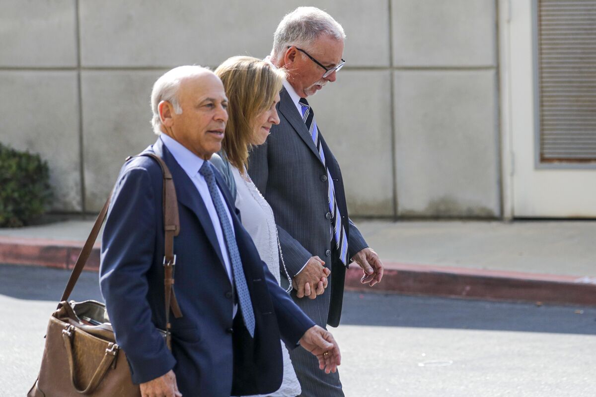 Three people in business wear walk outside a courthouse