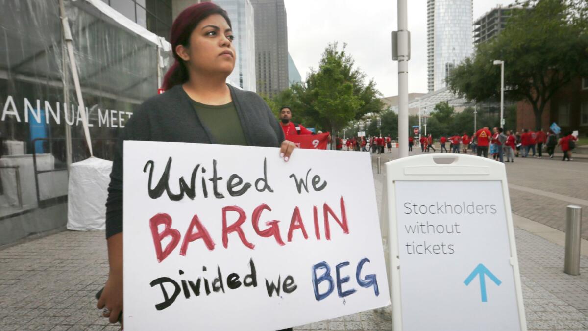 Union member Kristian Hernandez carries a sign during a Communication Workers of America protest outside AT&T's shareholders meeting in Dallas in April.