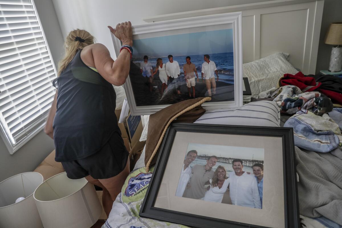 Kym Hilinski searches through boxes of family photos stored in her bedroom as her home is remodeled.