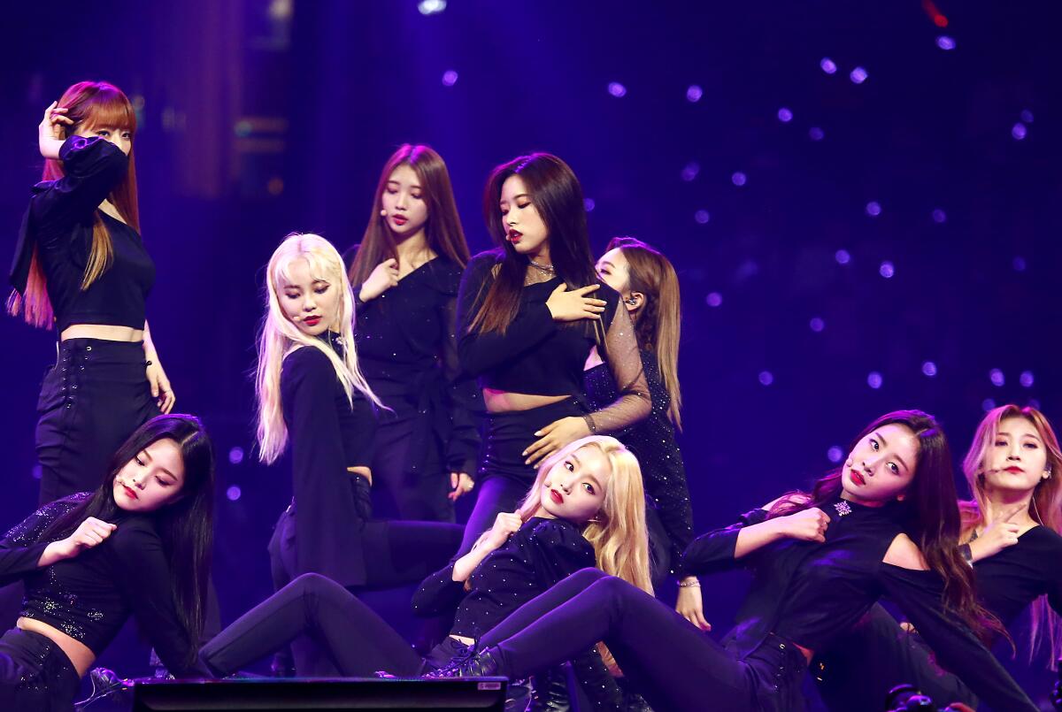 Nine members of K-pop girl group Loon, all wearing black, pose onstage during a performance