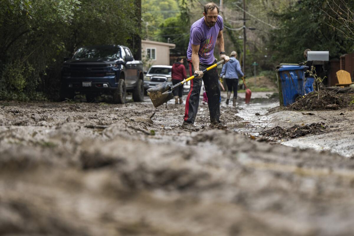 Matt O'Brien shovels mud from a friend's driveway after the San Lorenzo River overflowed in Felton, Calif.