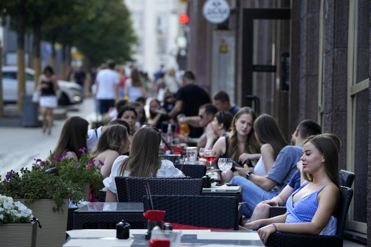 People relax after a hot day at an outdoor terrace of a restaurant in Moscow, Russia, Wednesday, July 14, 2021. The Russian capital recorded new record temperatures amid a heat wave this month with today's temperatures forecast 33 degrees Celsius (91,4 Fahrenheit). (AP Photo/Alexander Zemlianichenko)