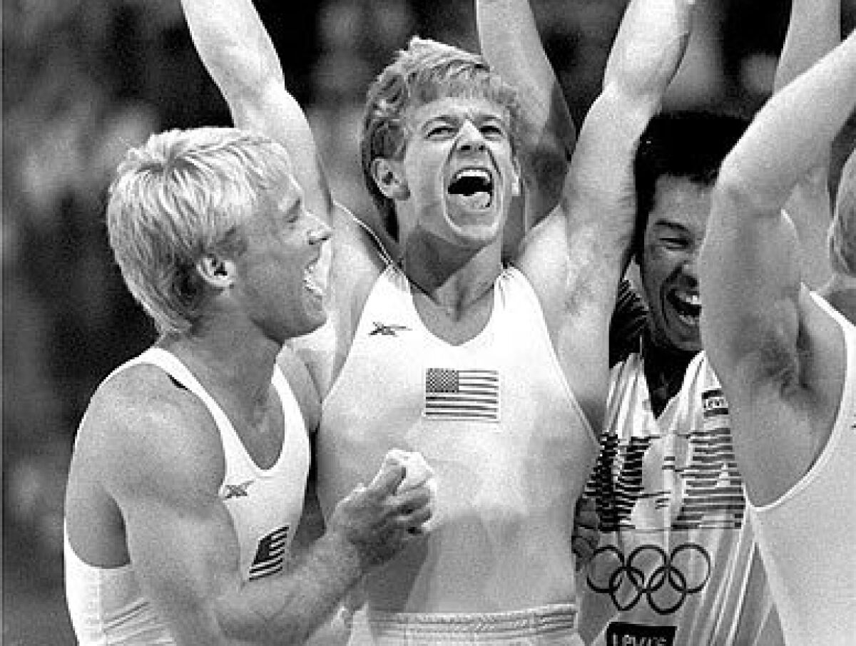 Bart Conner, left, and Peter Vidmar, center, celebrate following the U.S. men's gymnastic team's gold medal.