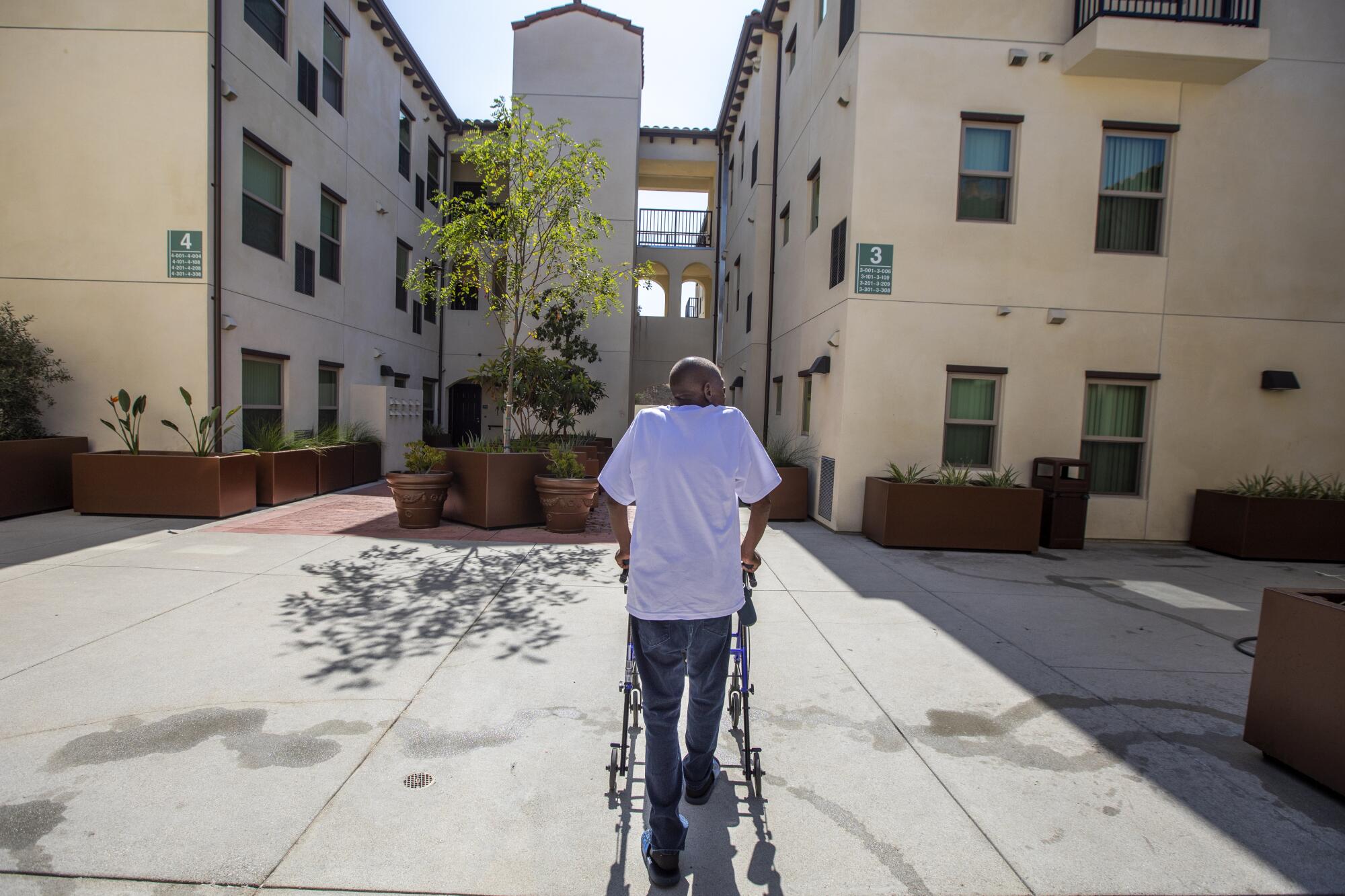 Wallace Harris walks through the courtyard of Washington View Apartments, his new home near USC.