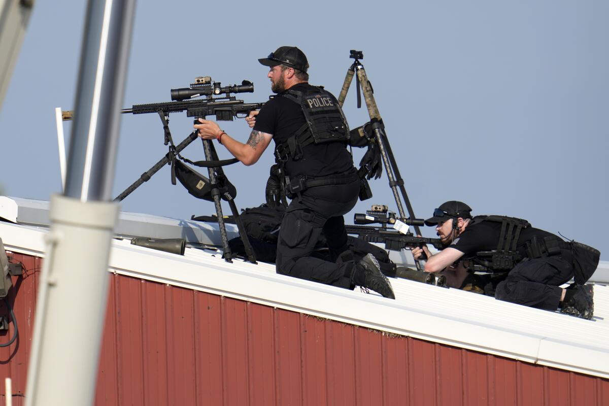 Men in dark uniforms positioned behind guns on tripods on a roof