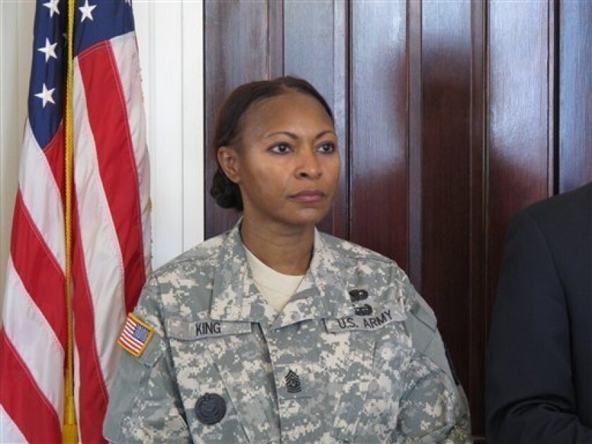 Command Sgt. Maj. Teresa King listens as her lawyer tells reporters she is getting her job back in Columbia, S.C. on Friday, May 4, 2012. King was the first woman to command the Army's drill sergeant training before she was suspended in November. Her lawyer says the Army's investigation vindicated King. (AP Photo/Jeffrey Collins)