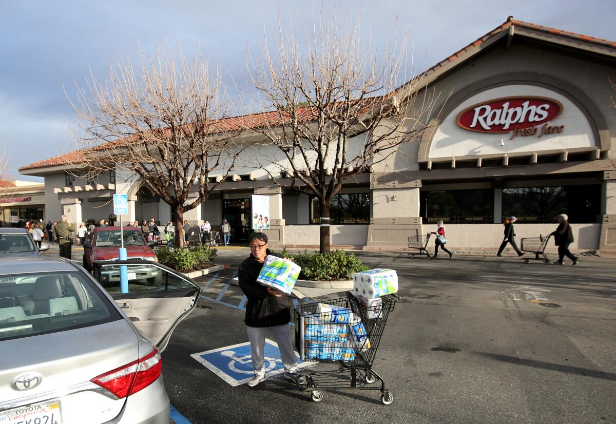 As Mike Lee of La Crescenta loads paper towels, toilet paper and water into his car, dozens still waited in line to enter the Ralphs supermarket in La Cañada Flintridge on Tuesday.