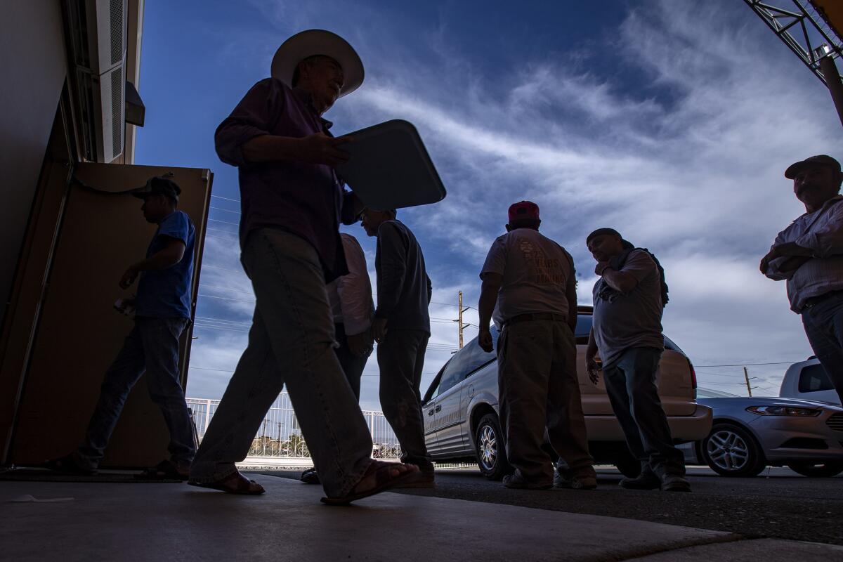 Migrant farmworkers staying the night at Our Lady of Guadalupe Shelter stand in line for dinner.