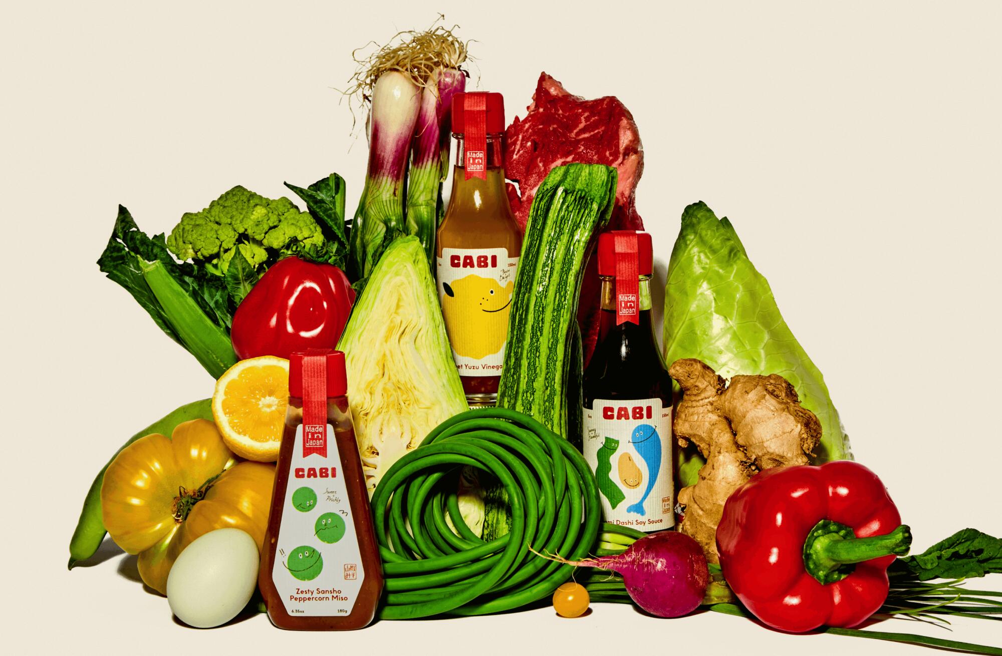 Bottles of Cabi sauces surrounded by vegetables and eggs.