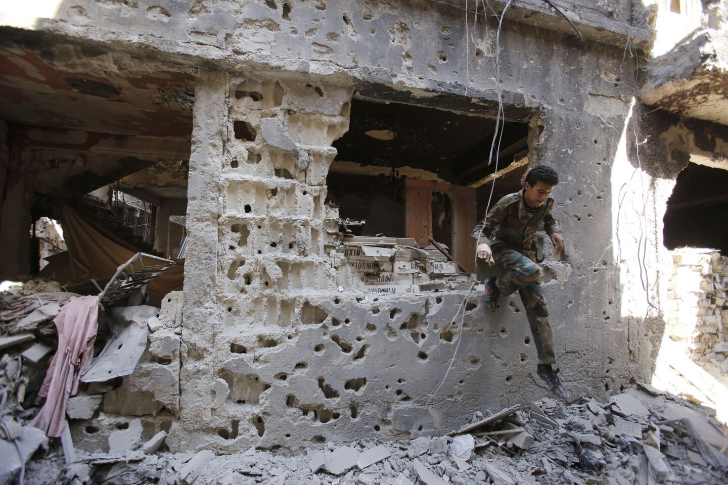 A fighter of the Popular Front for the Liberation of Palestine General Command, allied with Syrian President Bashar Assad, jumps through the window of a destroyed building in the Yarmouk refugee camp in Damascus.